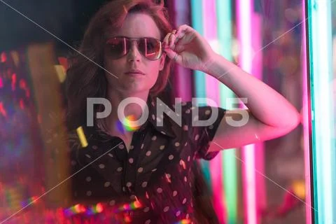 Cinematic night portrait of girl with sunglasses and neon lights Stock Photos
