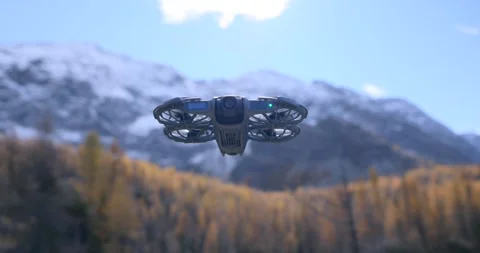 Cinematic orbit shot around a compact drone hovering before snowy mountain Stock Footage 343927747