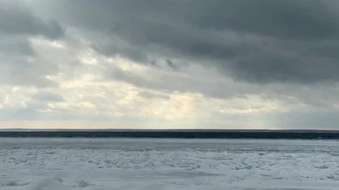 Cinematic panning of dark storm clouds over frozen lake ice floes in winter Stock Footage 325477801