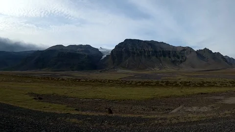 Cinematic panorama of a silty glacial stream and distant mountain glaciers Stock Footage 334063216
