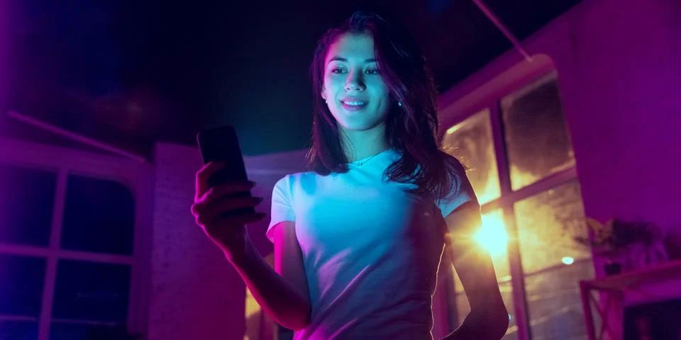 Cinematic portrait of handsome young woman in neon lighted interior Stock Photos