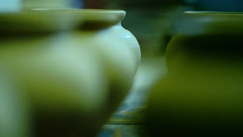 Cinematic rack focus shifting between rows of raw clay pots. Stock Footage 328925528