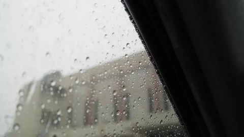 Cinematic Raindrops on Car Window Pane with Blurred Urban Building Background Stock Footage 339196076