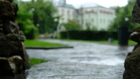 Cinematic raindrops falling on stone pavement in summer park 库存影片 333710995