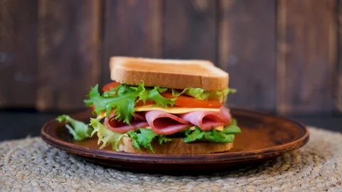 Cinematic rotating sandwich with layers of ham cheese and vegetables Vídeos de archivo 332788854