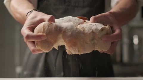 Cinematic shot: Break a bread. A view of male's hand breaking a loaf of fresh Stockbeeldmateriaal 139152244