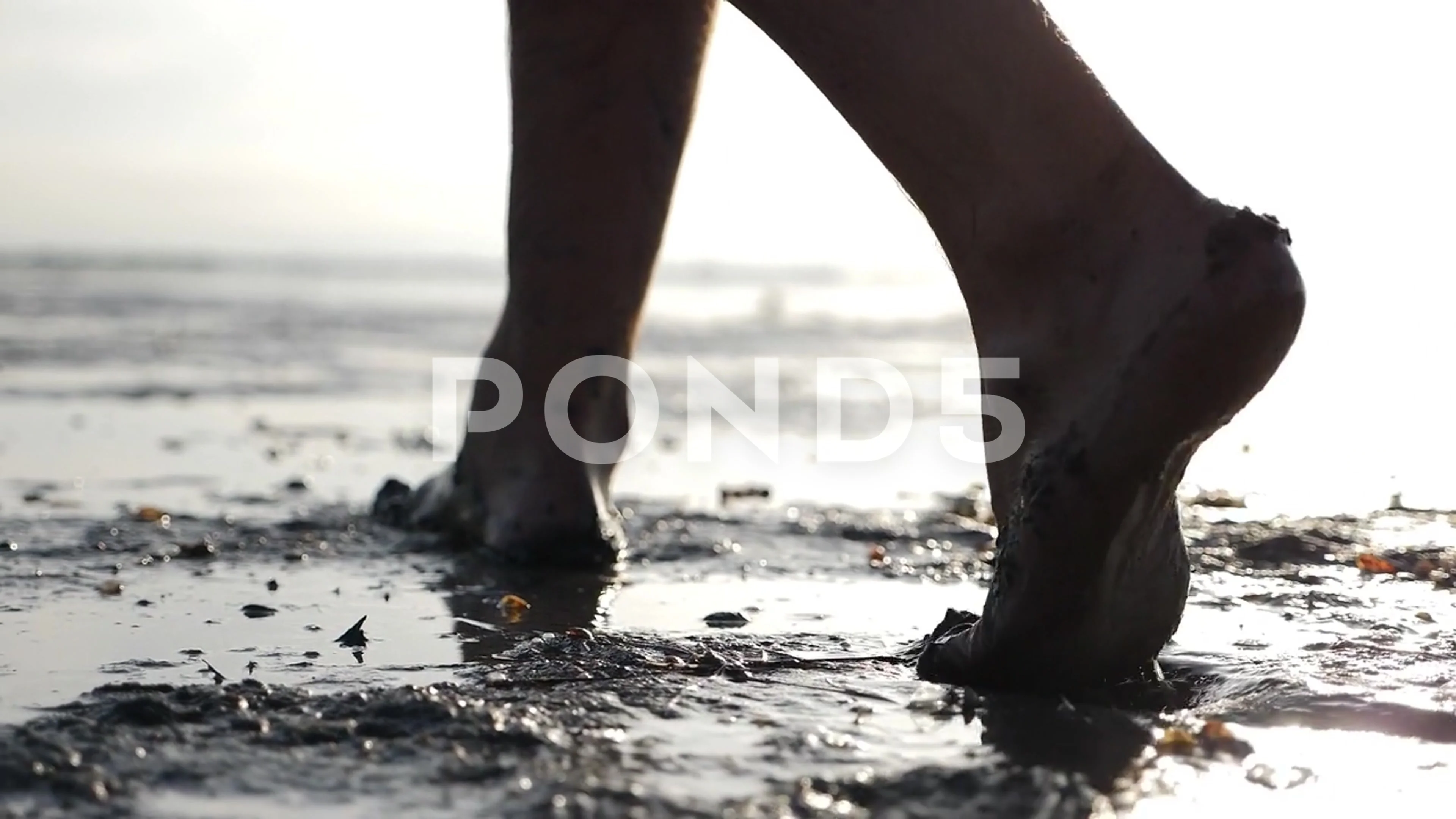 Cinematic shot of man with dirty feet walking barefoot making traces near  pond.