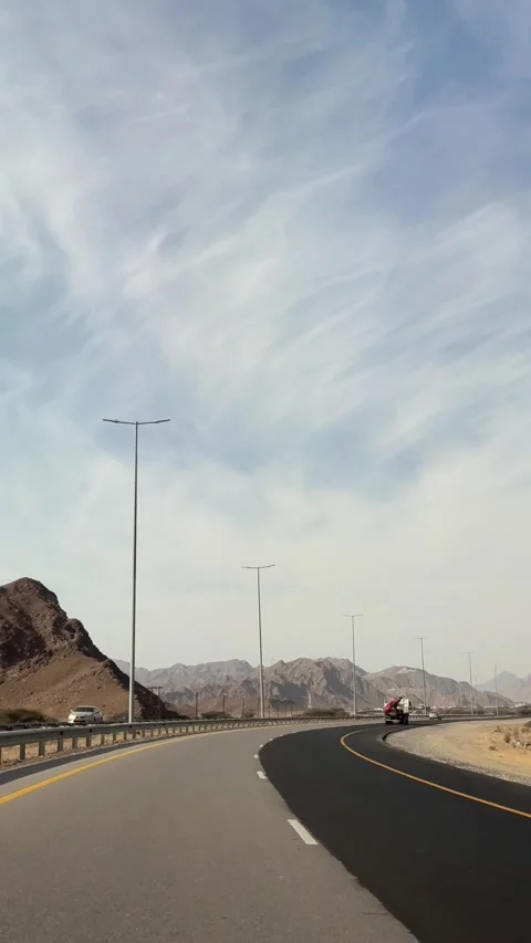 Cinematic shot of motorcycle navigating winding mountain highway under bright Stock Footage 324807460