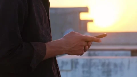 Cinematic shot of a person using a mobile device on a rooftop at dusk 库存影片 333451369