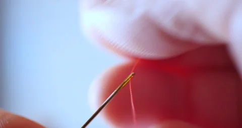 Cinematic shot of red thread passing through sewing needle. man sewing project Stock Footage 140975087