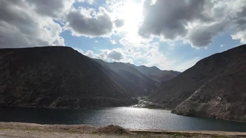 A Cinematic Side View of a Deep Green Lake Surrounded by Dark Mountains, Und Stock Footage 289188280