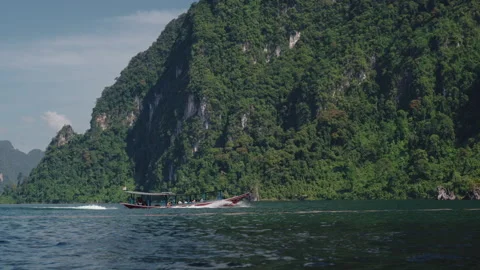 Cinematic Side View of Traditional Longtail Boat Speeding Past Majestic 库存影片 334643763
