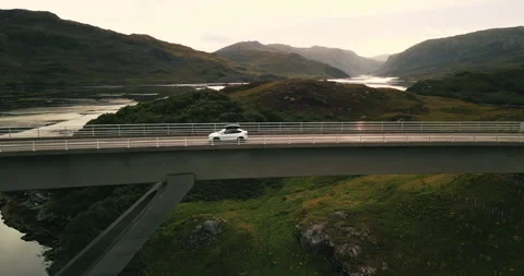 Cinematic side view of white car driving on iconic Kylesku Bridge with epic Stock Footage 288225537