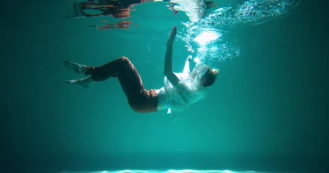 Cinematic side view, young beautiful woman slowly sinks deep under water Stock Footage 170154754