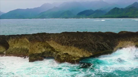 Cinematic slow motion drone shot of ocean waves on rocky island Stock Footage 336574667