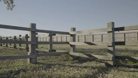 Cinematic slow-motion push in pull back of wooden fence rails in peaceful park Stock Footage 328254913