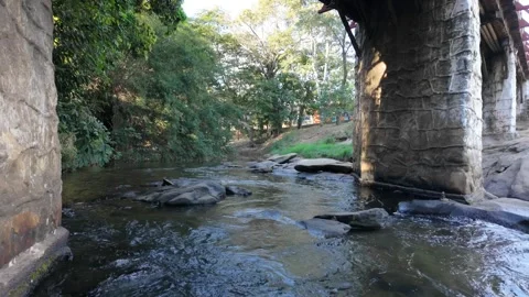 Cinematic slow motion of river rapids flowing under rustic stone bridge Stock Footage 339604578