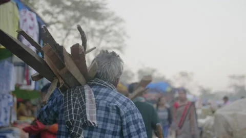 Cinematic slow motion shot of old man walking with wooden trunks to make a fire Video stock 140036710