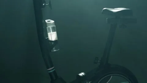 Cinematic Slow Pan Upwards on Empty Stationary Bike in Smoky Dark Studio with Stock Footage 313060869