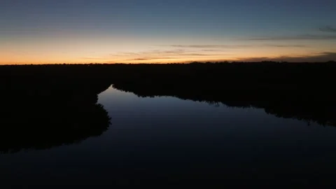 Cinematic sunrise pullback over mangrove wetlands and reflective waterways 스톡 동영상 344299454