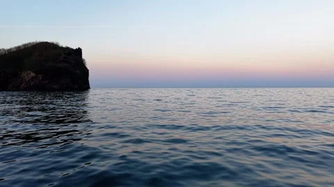 Cinematic Sunset Drone Flight Near Sea Surface with Island on the Left Vídeo Stock 334239449