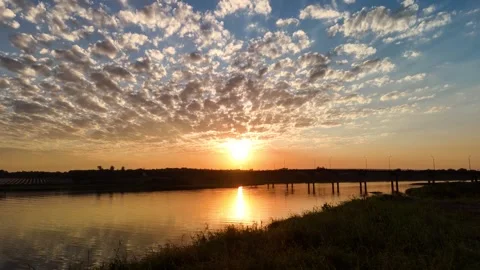 Cinematic sunset over calm river with scattered altocumulus clouds and brid.. Stock Footage 337604294