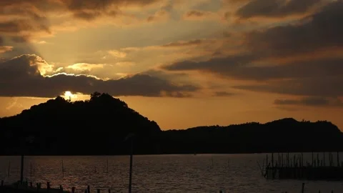 Cinematic Sunset Over Tropical Mountains Tilting Down to Golden Sea Ripples Video stock 334641453