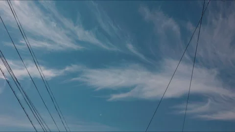 Cinematic time lapse clouds moving fast over power lines against a blue sky Stock Footage 342449834