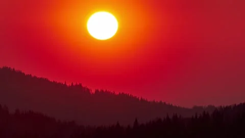 Cinematic time lapse of vibrant red sunset over mountain forest silhouette Stock Footage 336395135