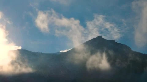 Cinematic timelapse of clouds moving across a mountain peak at sunrise Stock Footage 318194680