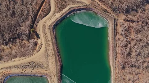 Cinematic Top-Down Aerial of an Emerald Green Reservoir with Frozen Ice Stock-Footage 330973196