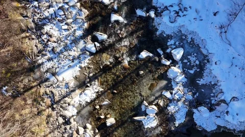 Cinematic Top-Down Drone View of Mountain Stream Through Snowy Landscape Stock Footage 331941699
