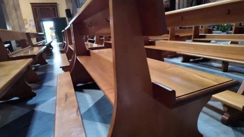 Cinematic tracking shot down the aisle of empty wooden pews in a historic church Stockbeeldmateriaal 338010427