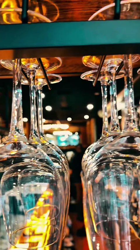 Cinematic Vertical Close-up of Clean Wine Glasses Hanging in a Dimly Lit Upscale Stock Footage 329241220