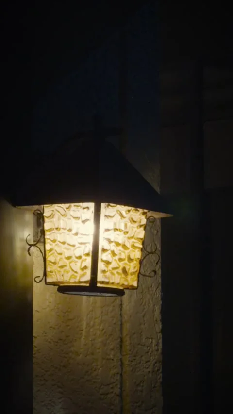 Cinematic vertical close-up shot of a warm glowing vintage porch lamp Vidéo 345489135