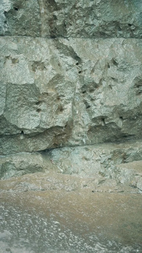 Cinematic vertical close-up shot of water gently flowing down a stone wall Vidéo 345458586