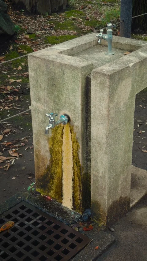 Cinematic vertical close-up of vintage stone drinking fountain with min Stock Footage 345514835