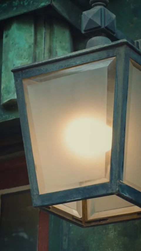 Cinematic vertical close-up of a warm glowing antique outdoor lamp with Stock Footage 345500028