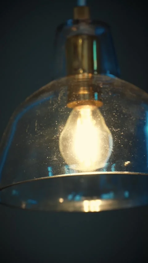 Cinematic vertical close-up of warm glowing vintage Edison light bulb Stock Footage 345700170