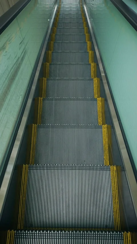 Cinematic vertical high angle shot looking down an empty modern glass escalator Vidéo 345458339