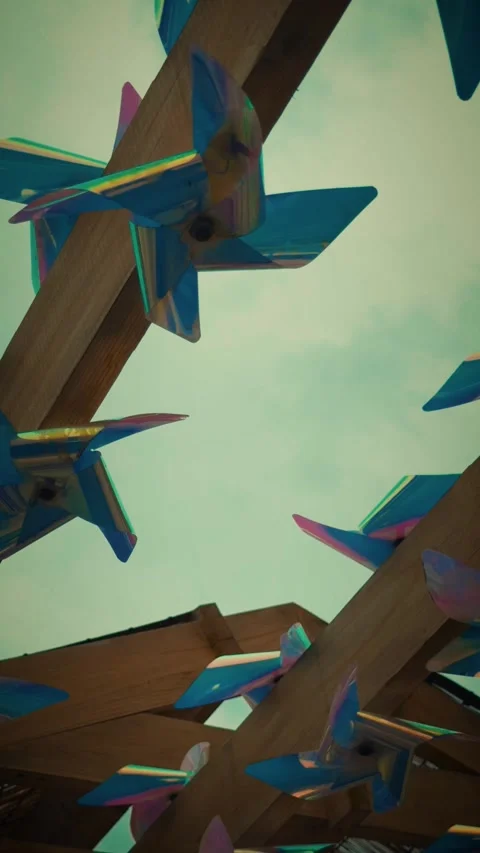 Cinematic vertical low angle shot of shiny iridescent pinwheels spinning Vidéo 345490327