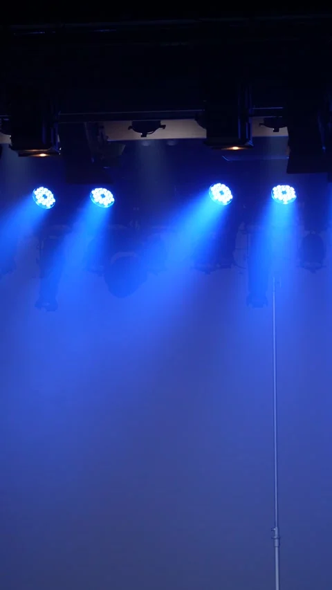 Cinematic vertical pan of empty stage lit by four bright blue lights Vidéo 345705317
