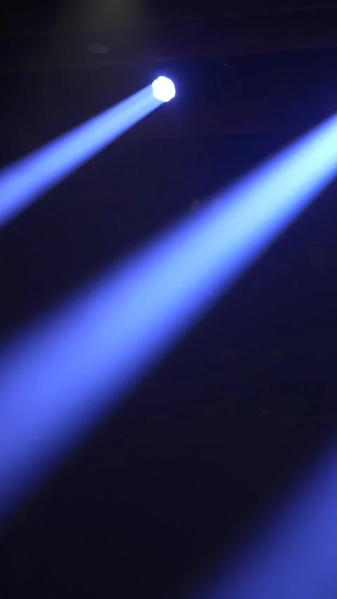 Cinematic vertical pan of two powerful blue stage spotlights beaming Vidéo 345705477