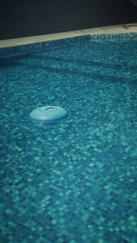 Cinematic vertical shot of a blue floating chlorine dispenser bobbing Vidéo 345504696