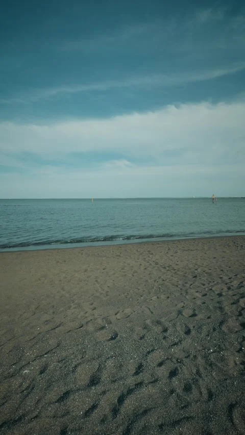 Cinematic vertical shot of a calm sandy beach with gentle ocean waves Vidéo 345456748