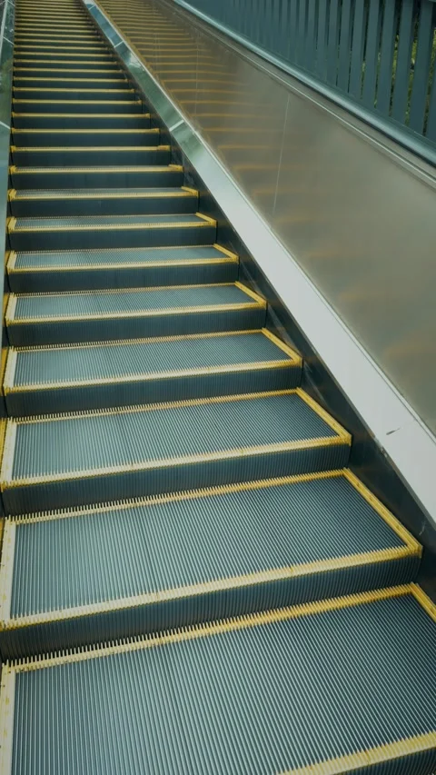 Cinematic vertical shot of an empty modern escalator moving upwards Vidéo 345458295