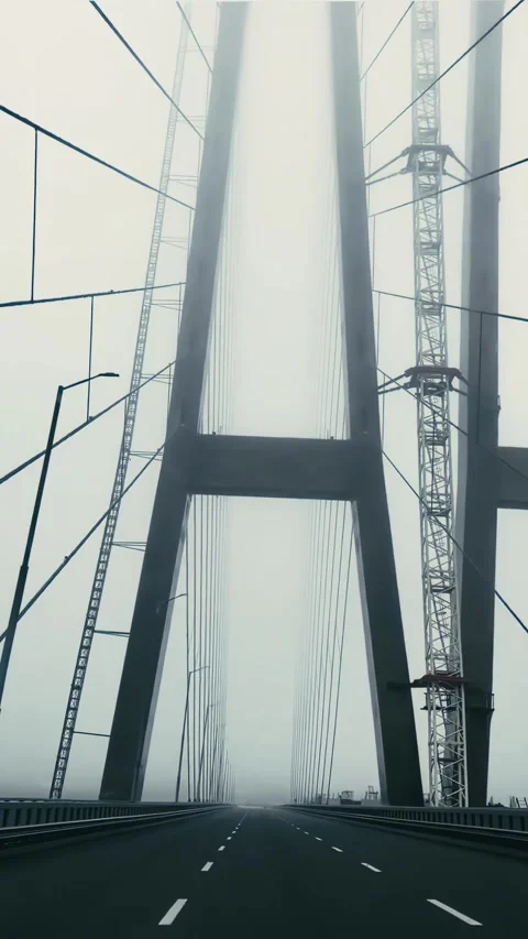 Cinematic vertical shot of a massive bridge disappearing into thick fog. Vídeo Stock 331993010