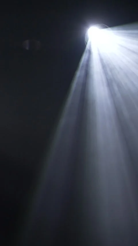 Cinematic vertical view of a single bright white spotlight casting volumetric li Vidéo 345705593