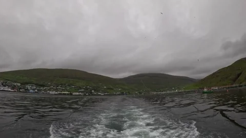 Cinematic view from the back of a moving ship leaving a Nordic fjord Stock Footage 339224439