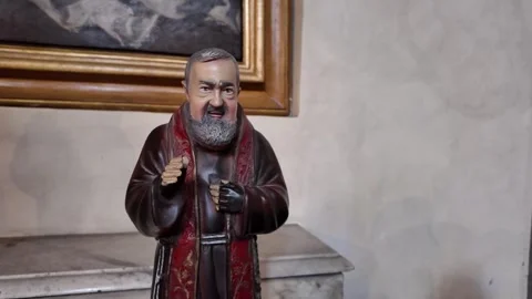 Cinematic View Of A Devotee Praying Before A Bronze Statue Of Padre Pio Stock Footage 338010456